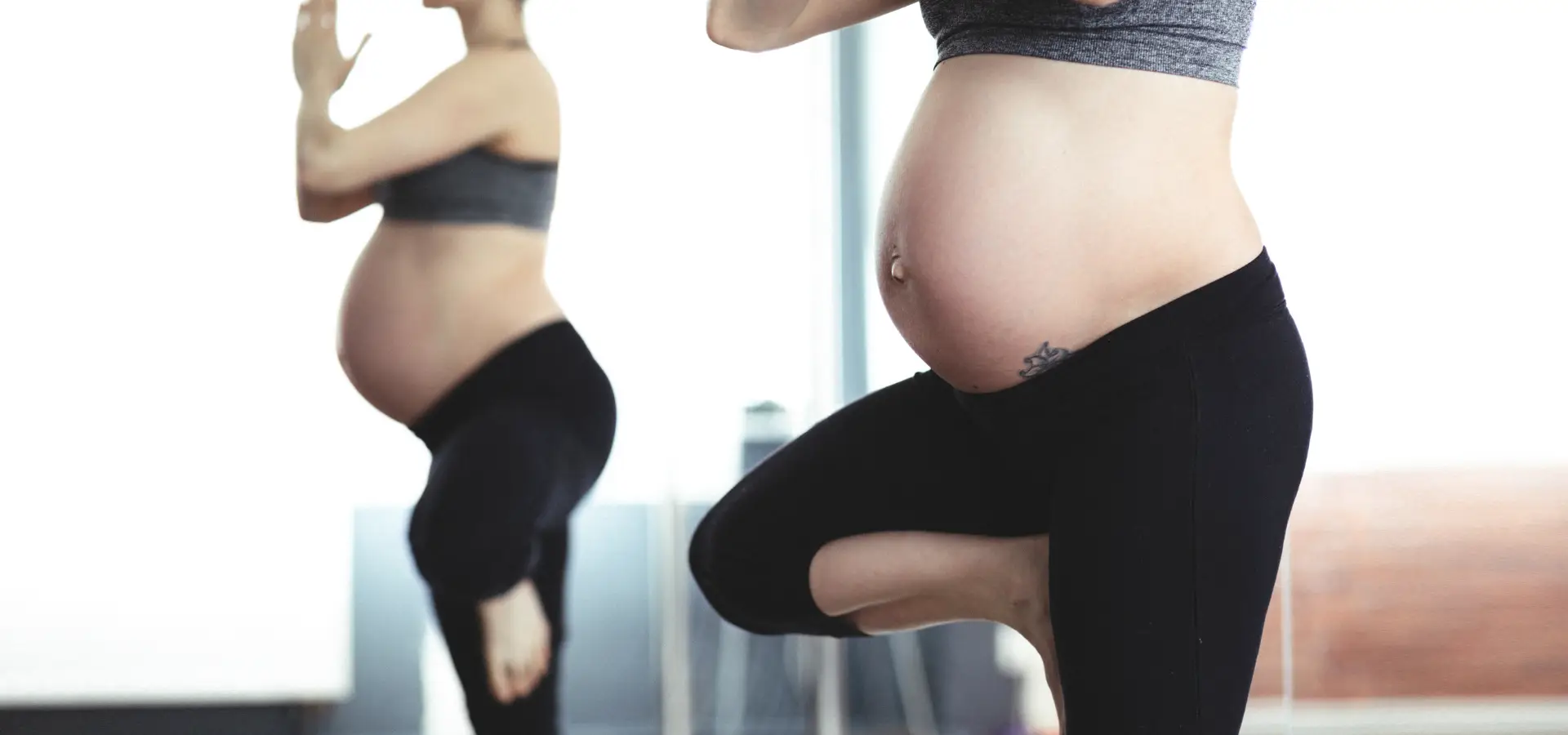 Schwangere Frau beim Yoga vor Spiegel.