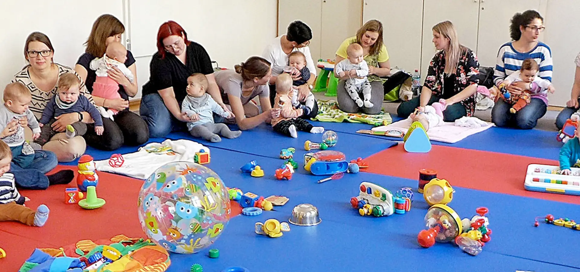 Mütter und Babys bei einer Spielgruppe mit Spielzeug.