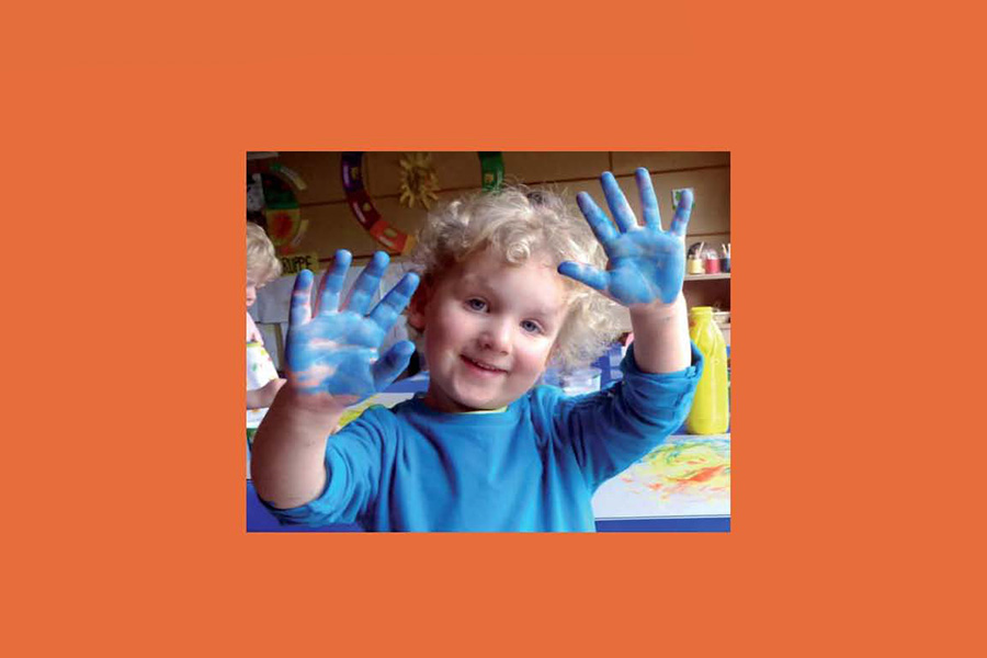Kind mit blauer Farbe an den Händen beim Spielen.