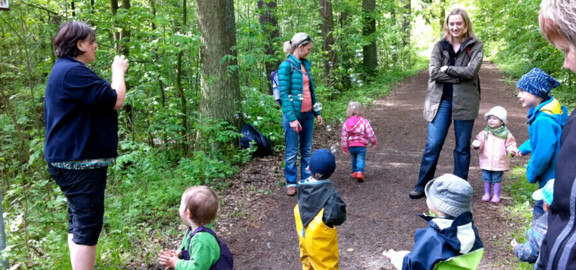 Gruppe von Erwachsenen und Kindern auf einem Waldspaziergang.