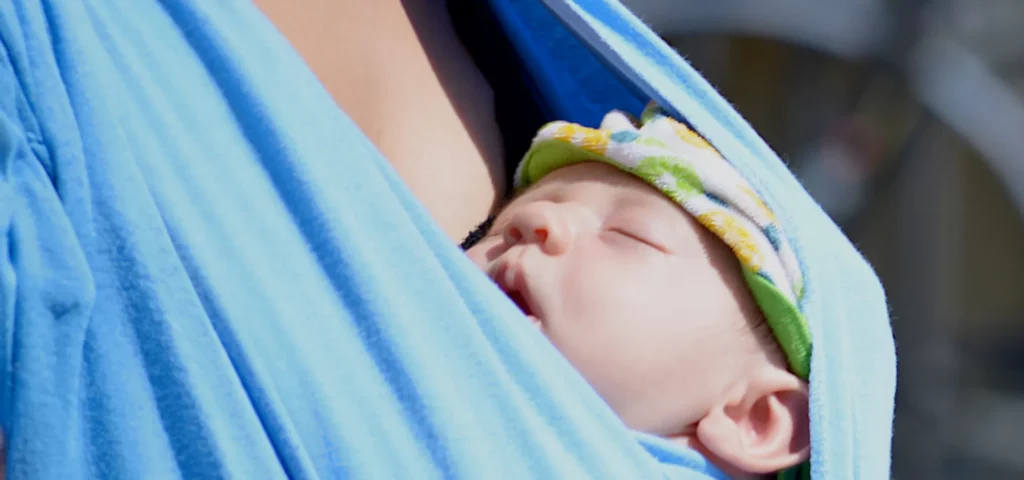 Schlafendes Baby in blauer Tragetuch.