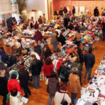 Beschäftigte Menschenmenge beim Flohmarkt mit Kleidung und Gegenständen.