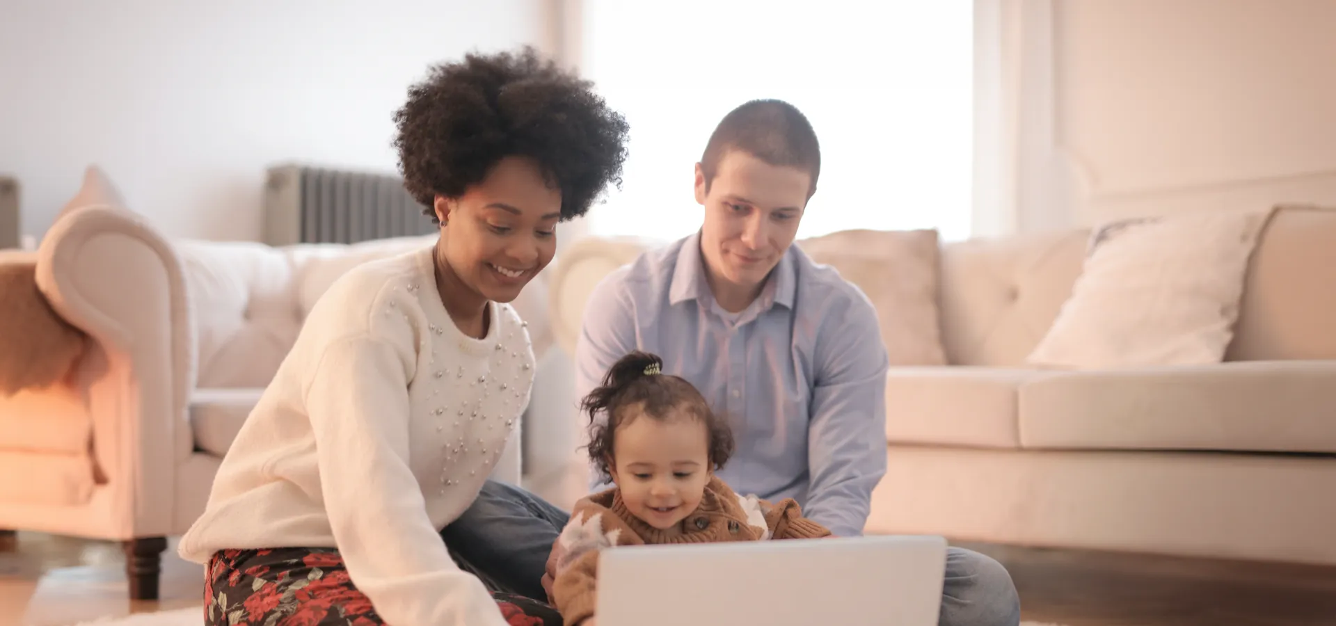 Familie mit Kleinkind schaut gemeinsam auf Laptop.