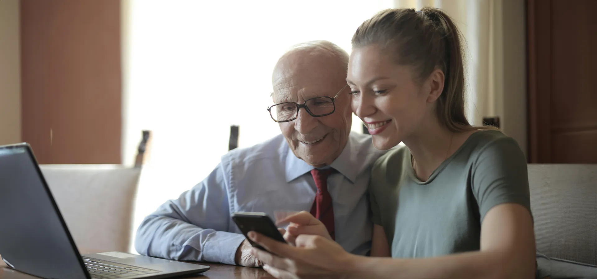 Älterer Mann und junge Frau betrachten Smartphone.
