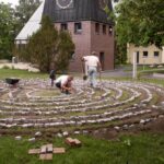 Zwei Personen gestalten ein steinernes Labyrinth im Garten.